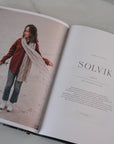 Open book with a photo of a person wearing a scarf and text on a marble surface