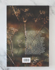 Book cover with text and plant imagery on a marble surface