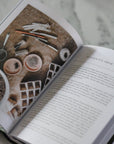 Open book with a decorative page featuring wooden objects on a marble surface