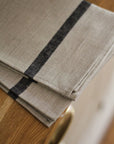 Folded beige towel with black stripes on a wooden surface