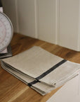 Folded beige towel with black strip on a wooden surface