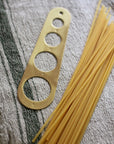 brass pasta measure hung on brass rail kitchen display