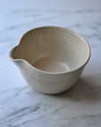 Beige ceramic mixing bowl on a marble surface