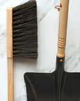 black metal dustpan with wooden handle and wooden brush