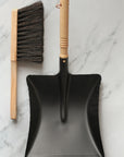 black metal dustpan with wooden handle and wooden brush