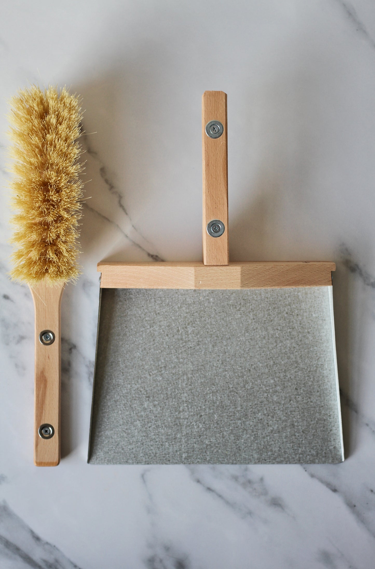 metal and wood dustpan and brush held together with magnets