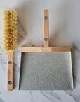 metal and wood dustpan and brush held together with magnets