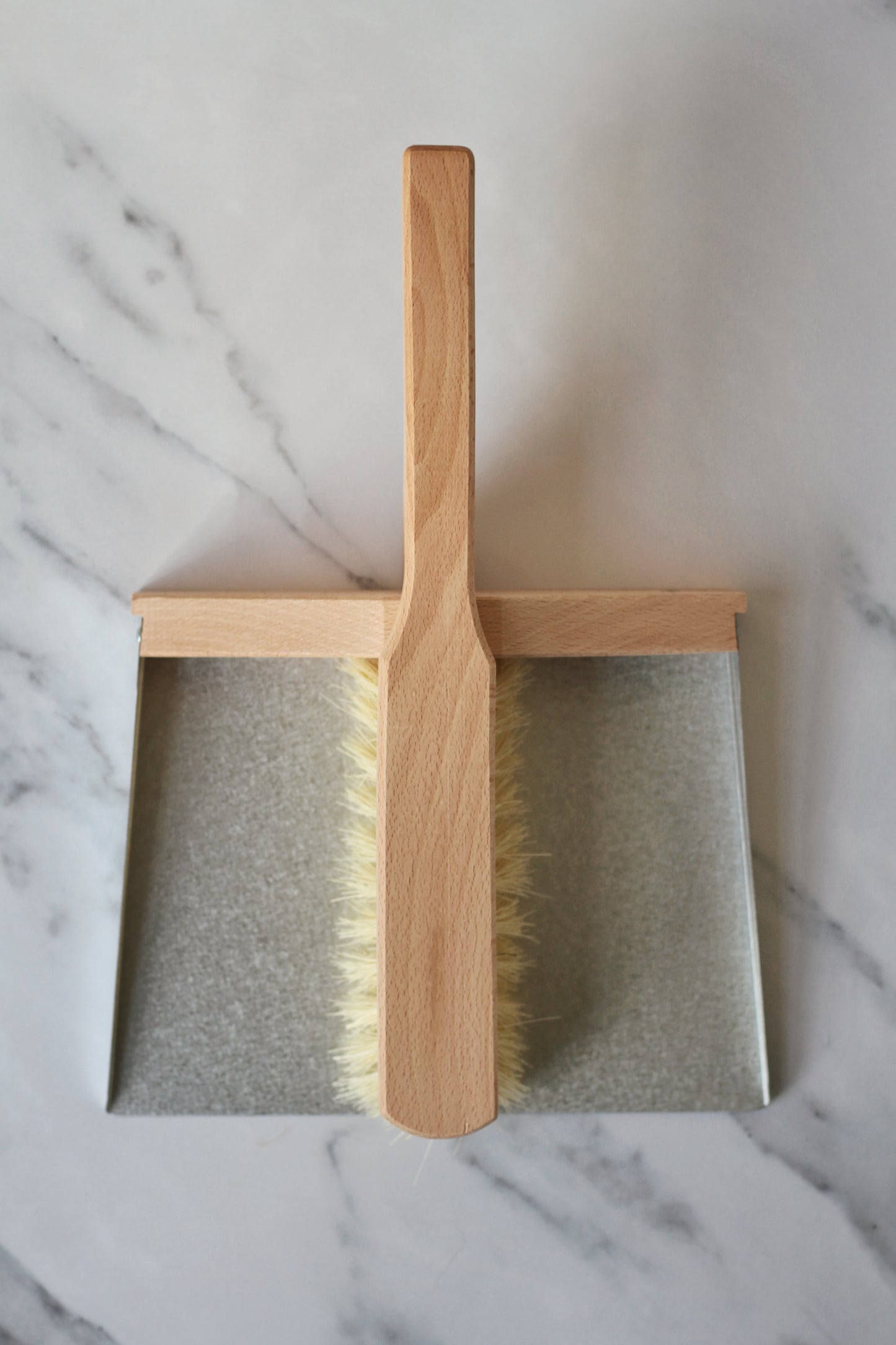 metal and wood dustpan and brush held together with magnets