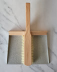 metal and wood dustpan and brush held together with magnets
