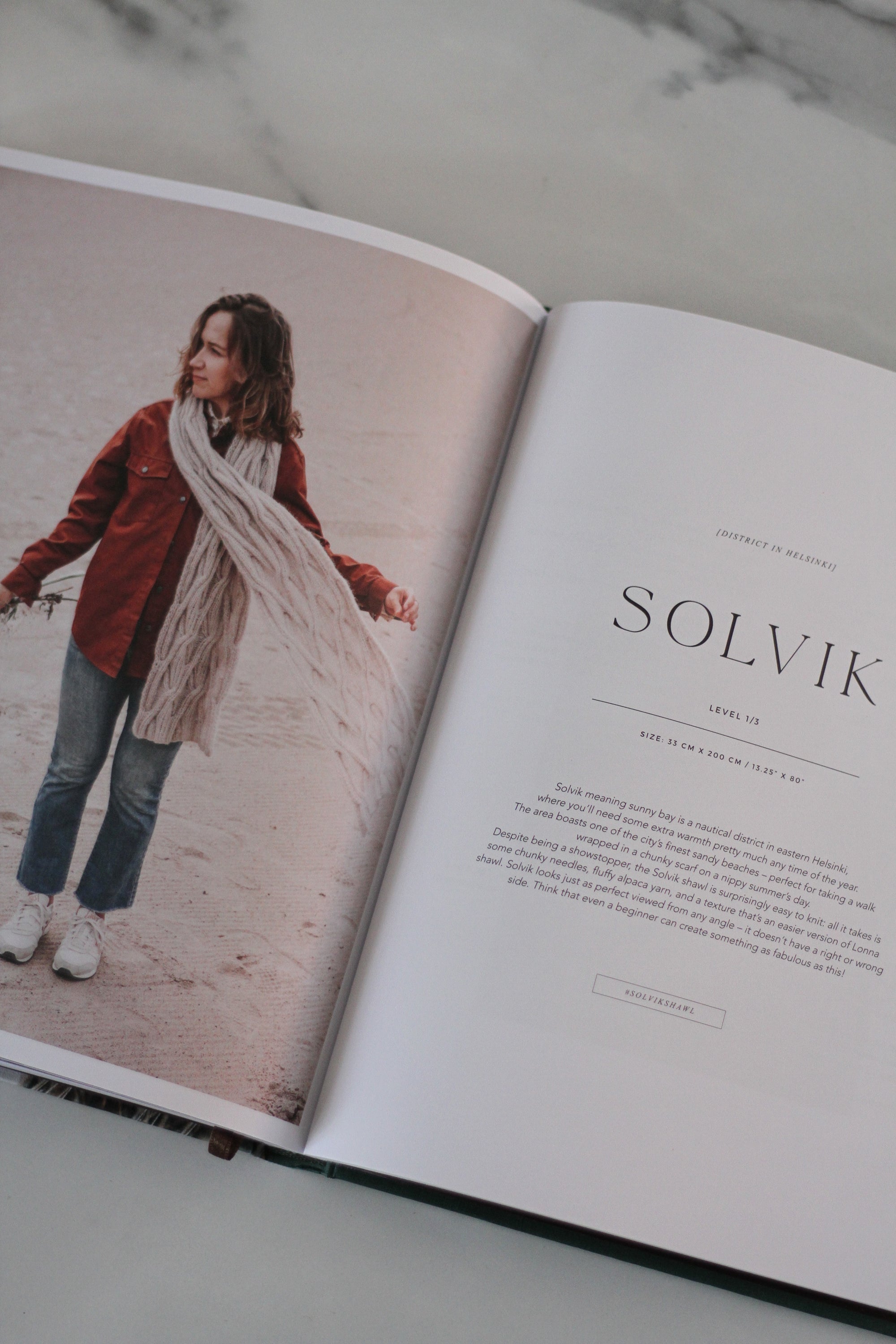 Open book with a photo of a person wearing a scarf and text on a marble surface