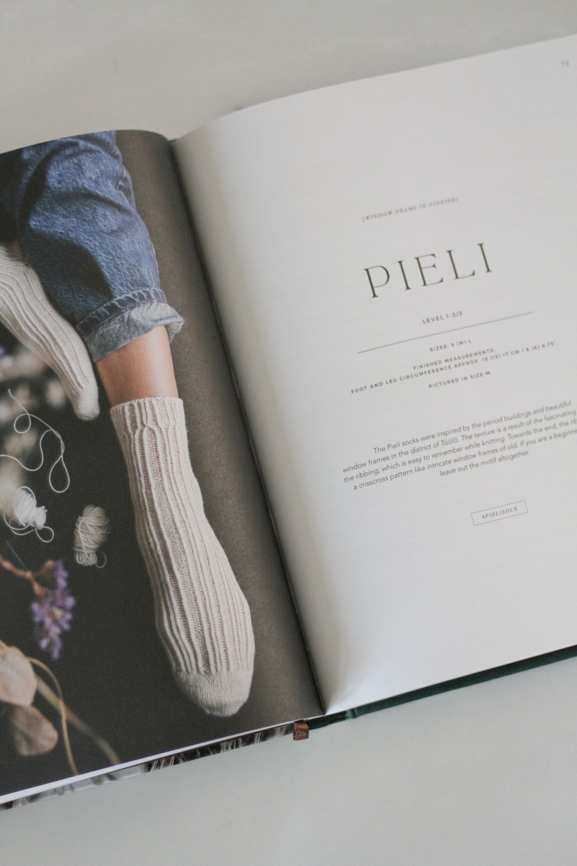 Open book with a page titled &#39;PIELI&#39; featuring a person wearing white socks and blue jeans.