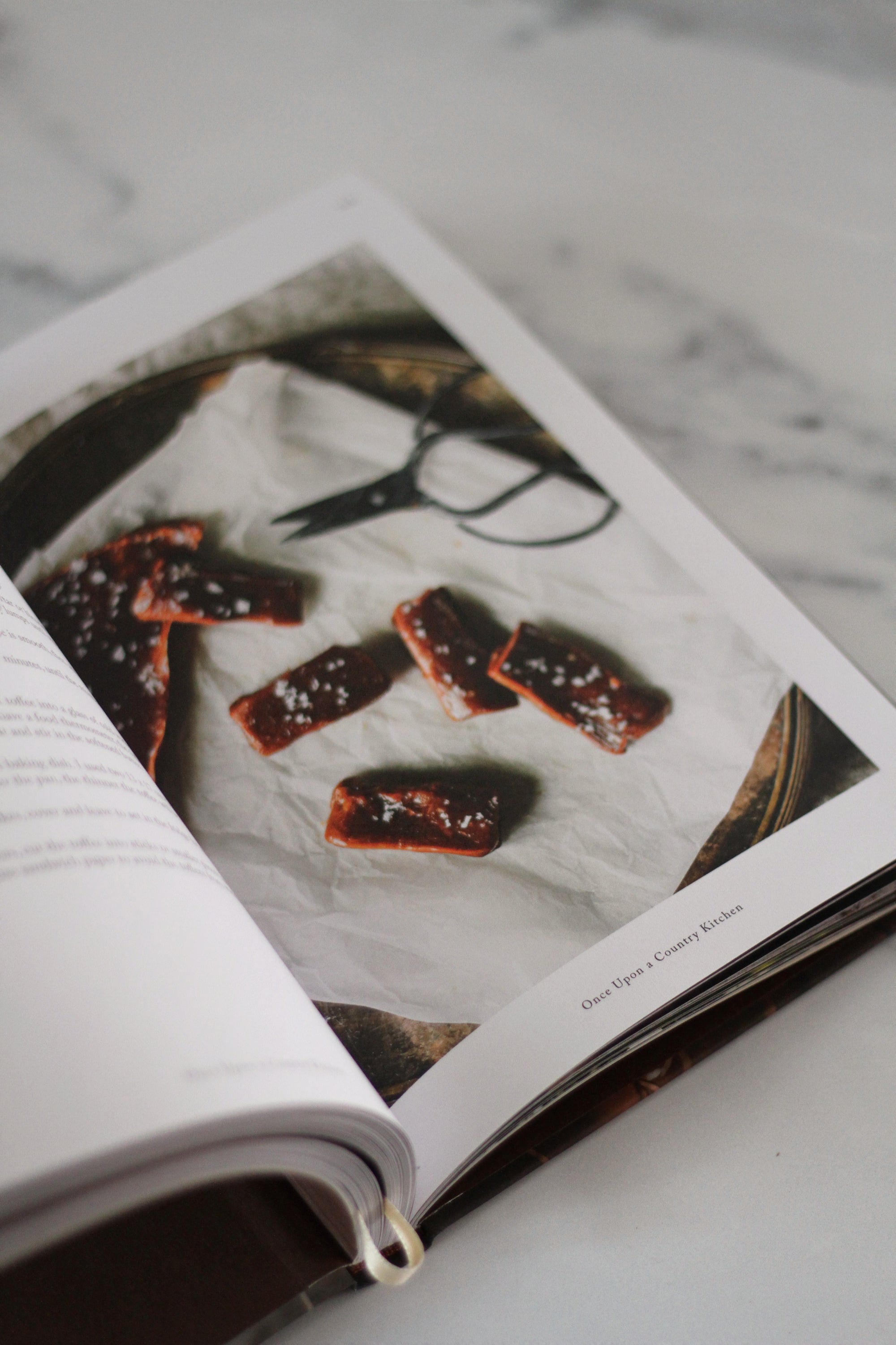 Open book showing a photograph of food on a marble surface