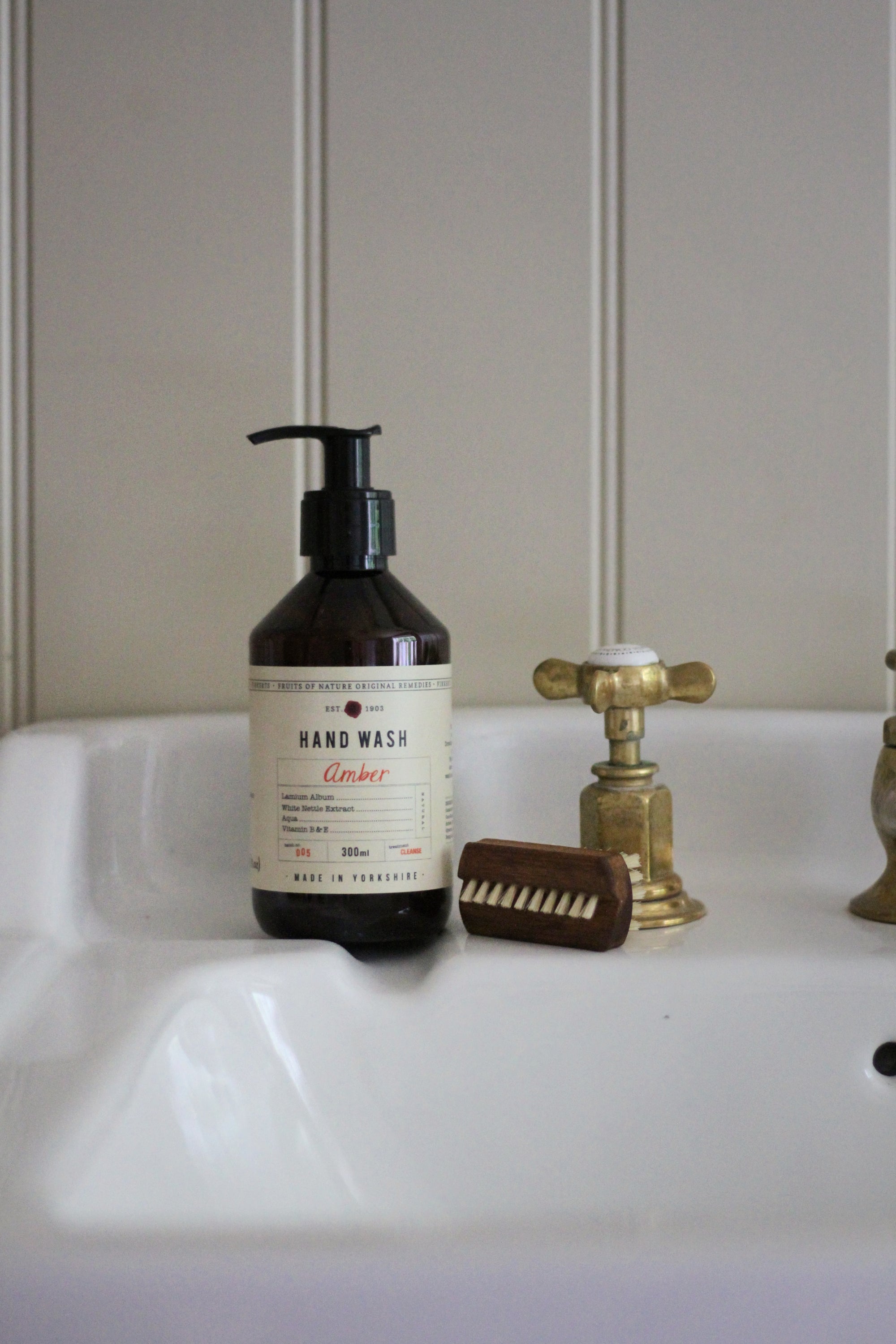 Hand wash bottle with pump, brush, and faucet on a sink