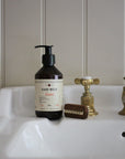 Hand wash bottle with pump, brush, and faucet on a sink