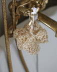 Brass shower head with a loofah hanging from it against a white background
