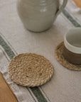 Jute coasters on a table with a ceramic vase and cup.