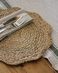 Woven placemat with cutlery and napkin on a wooden surface
