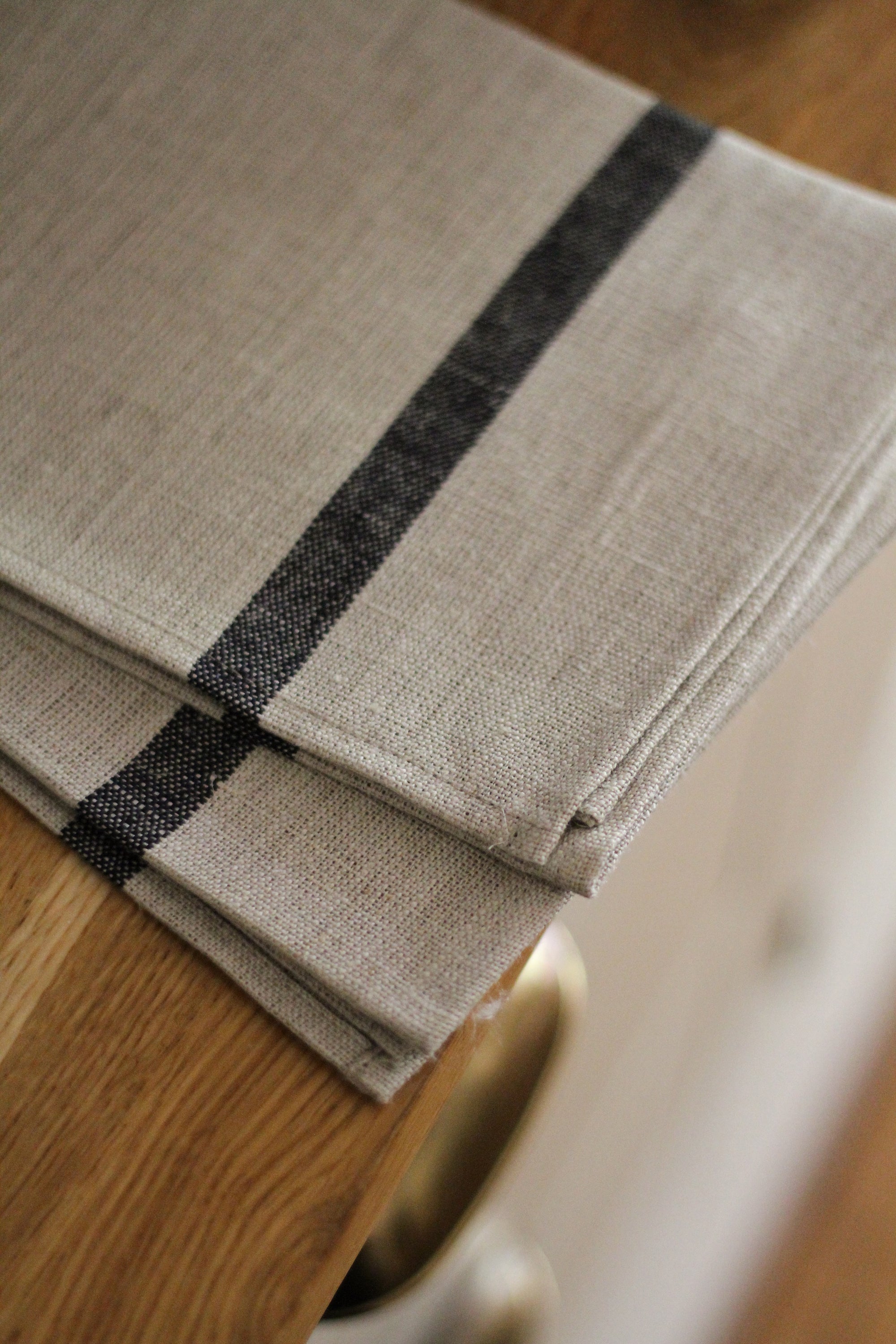 Folded beige towel with black stripes on a wooden surface