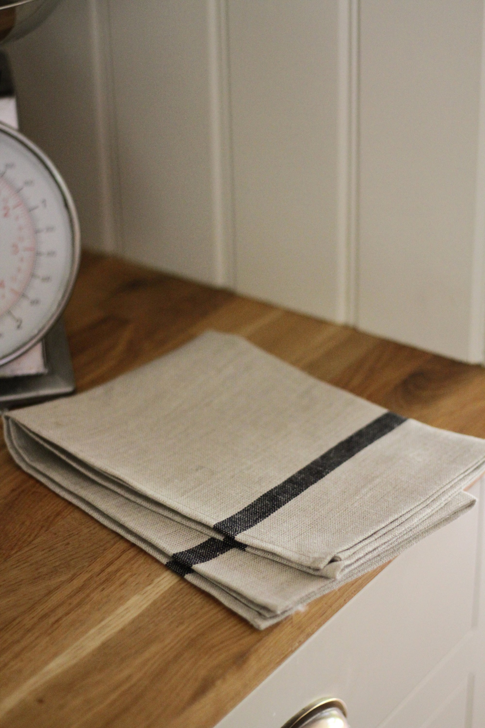 Folded beige towel with black strip on a wooden surface