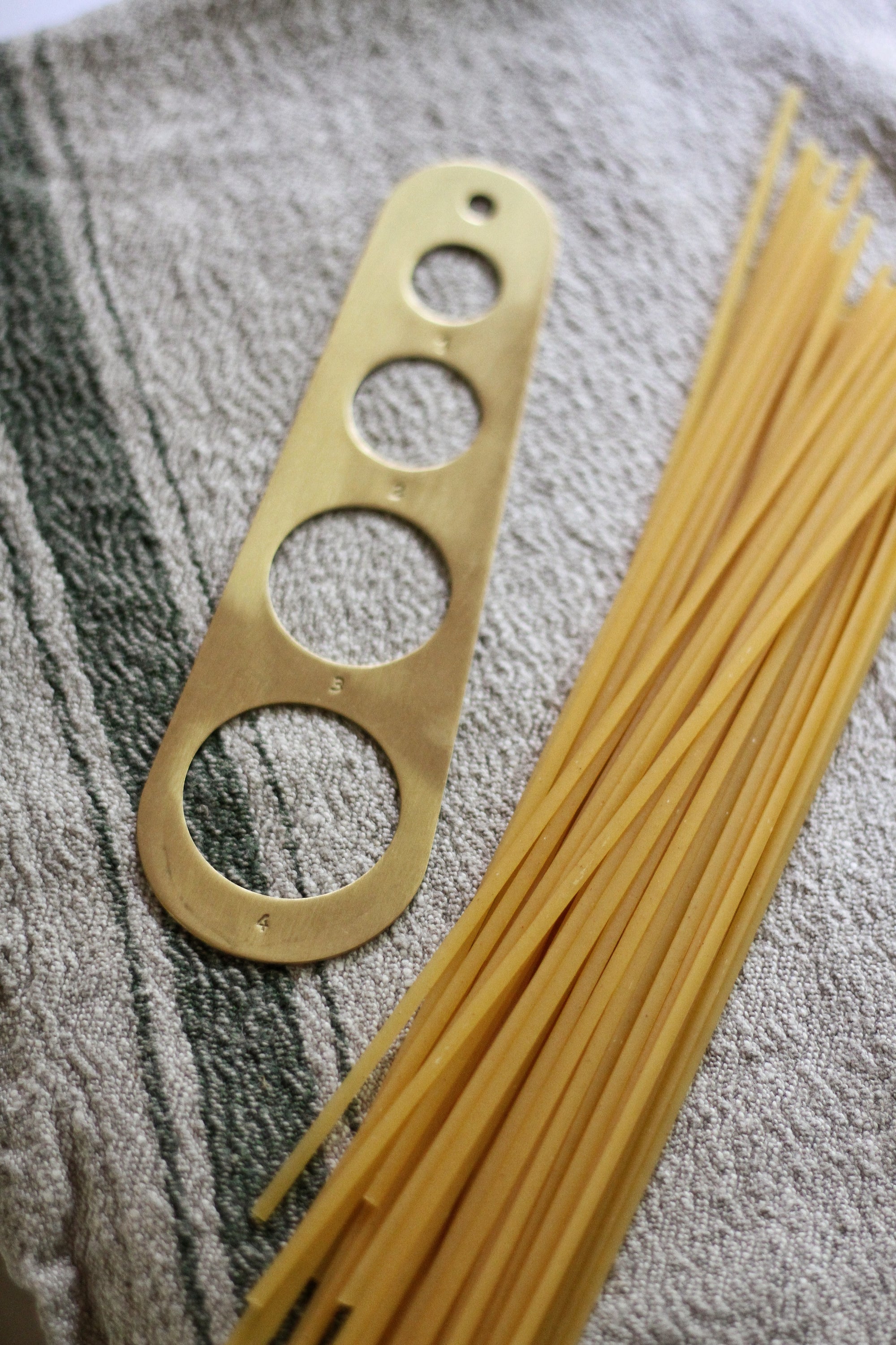 brass pasta measure hung on brass rail kitchen display 
