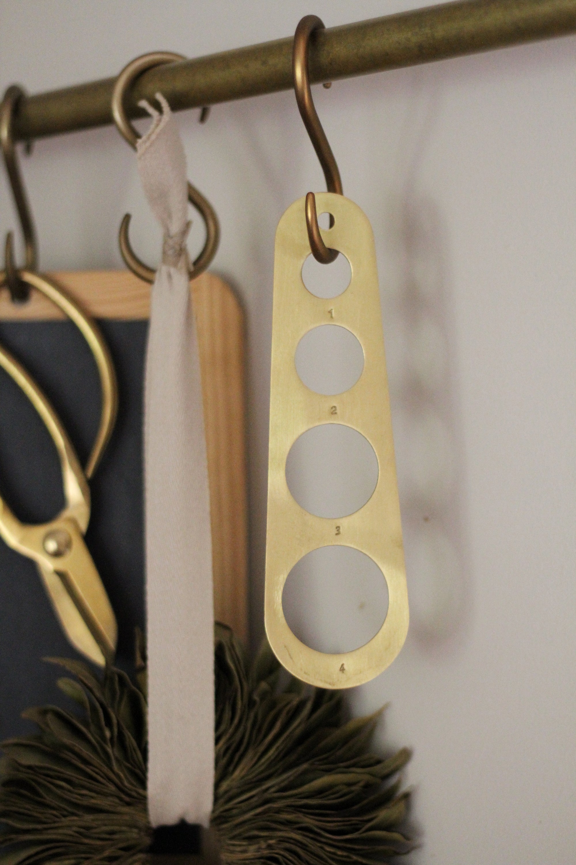 brass pasta measure hung on brass rail kitchen display 