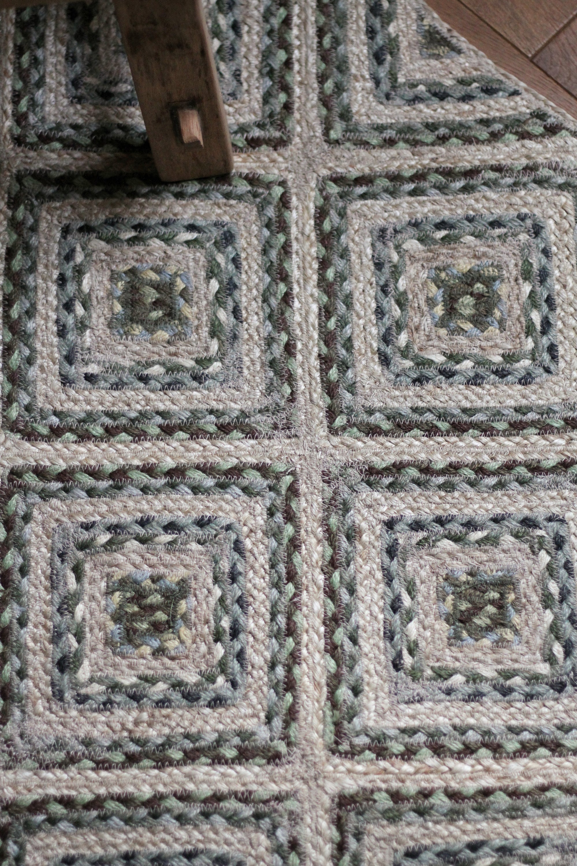braided jute rug in a square patchwork design in shades of green