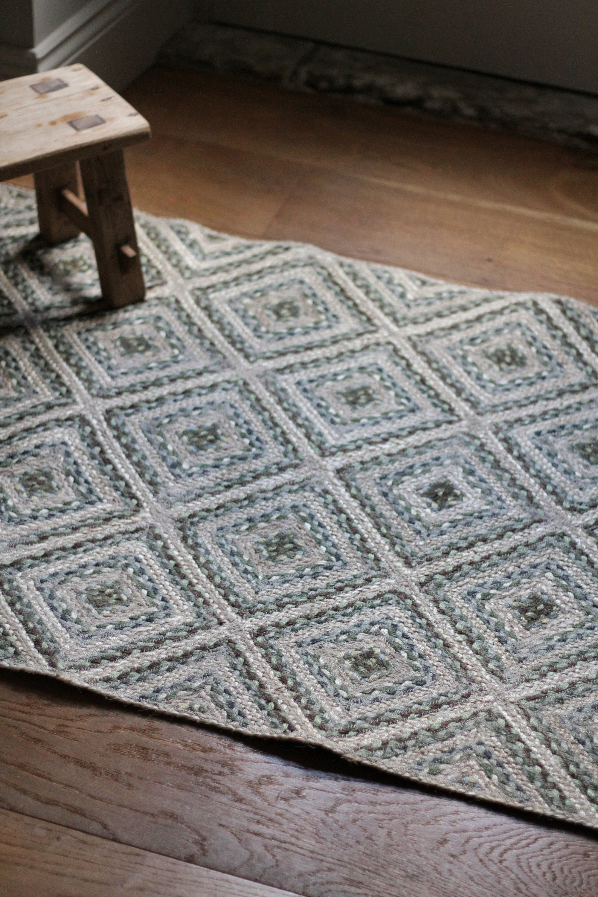 braided jute rug in a square patchwork design in shades of green