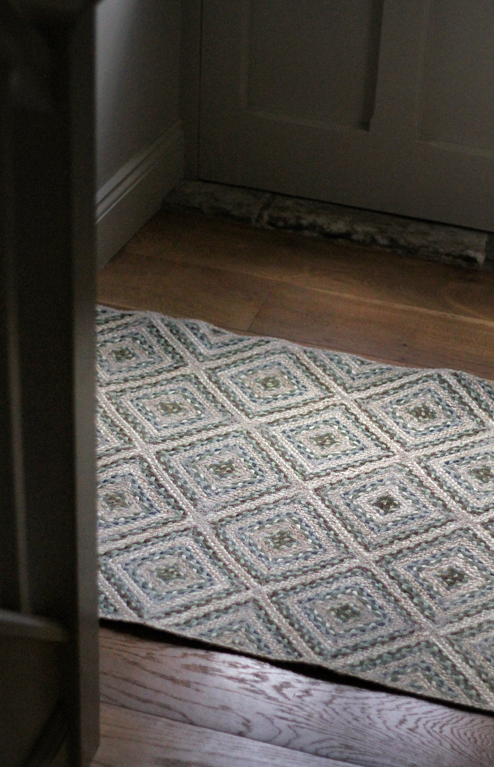 braided jute rug in a square patchwork design in shades of green