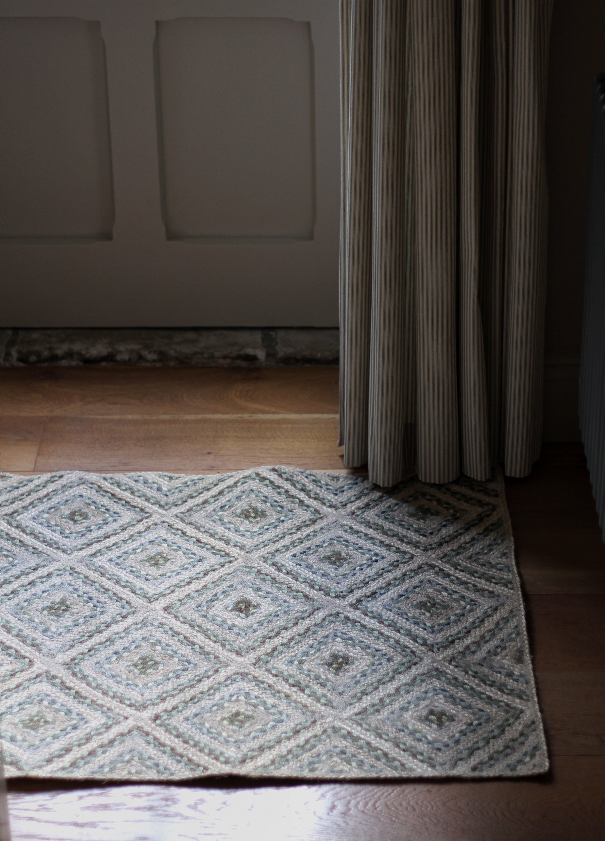 braided jute rug in a square patchwork design in shades of green