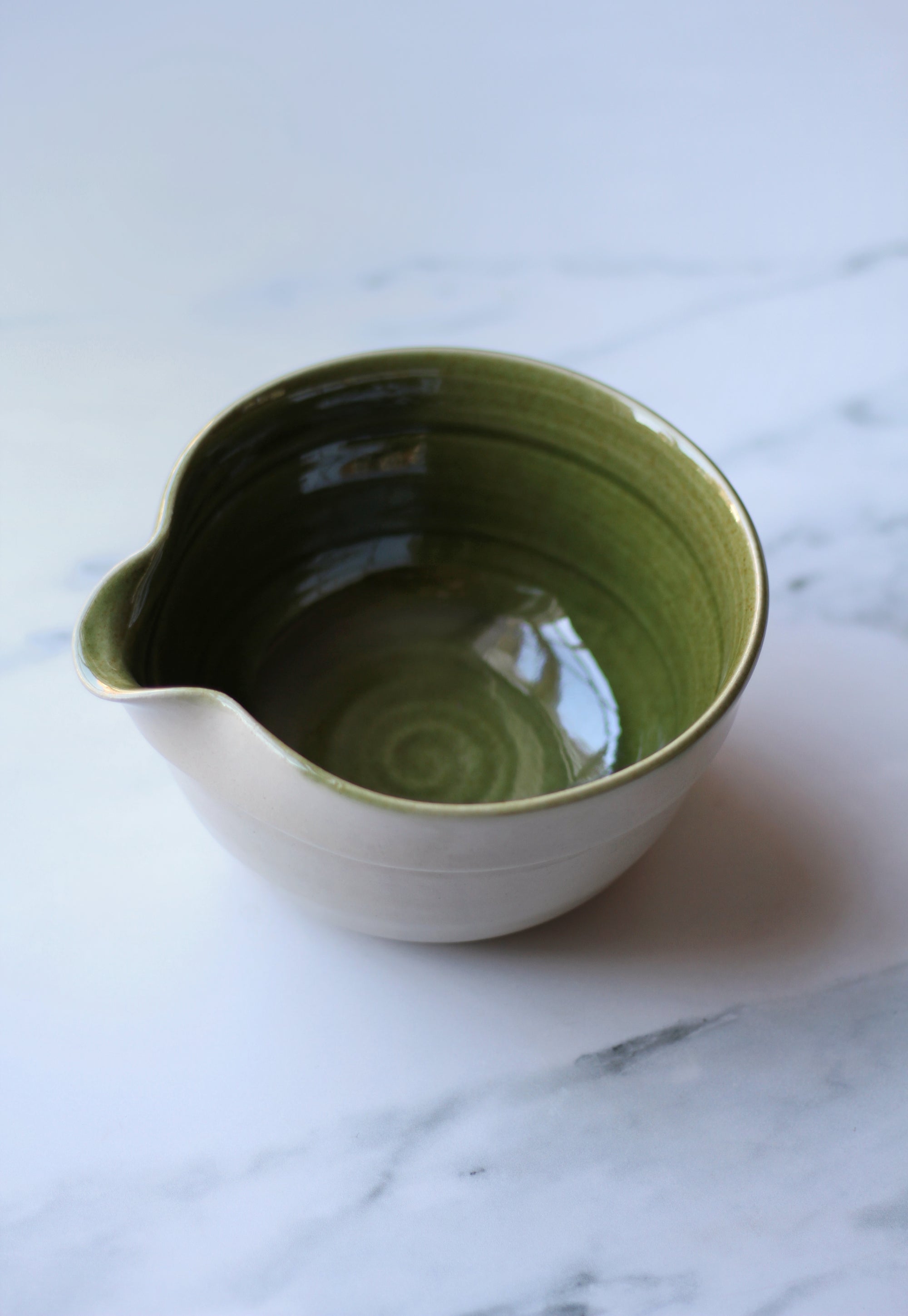 Green ceramic bowl on a marble surface