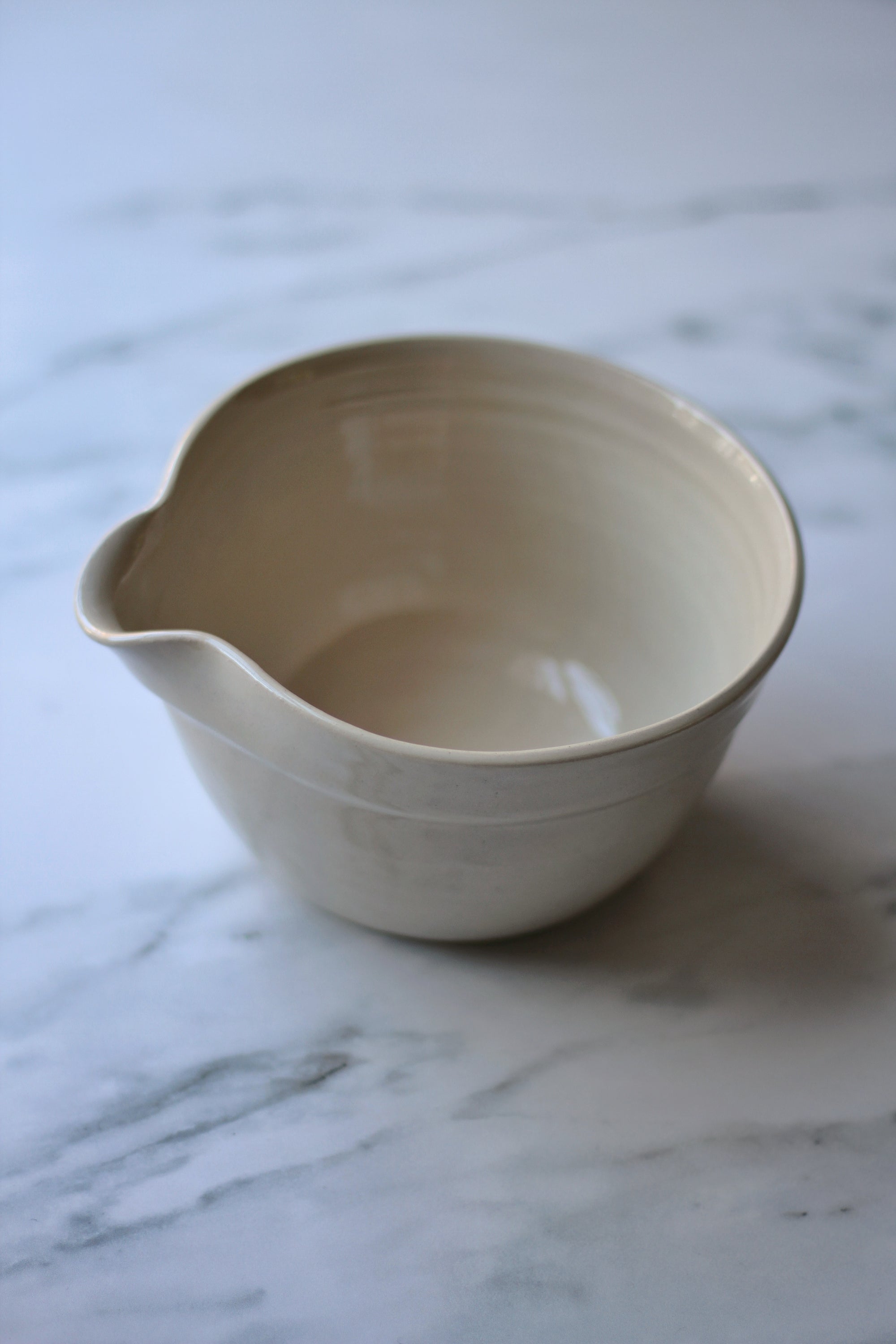 Beige ceramic mixing bowl on a marble surface