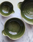 Three green ceramic bowls on a marble surface