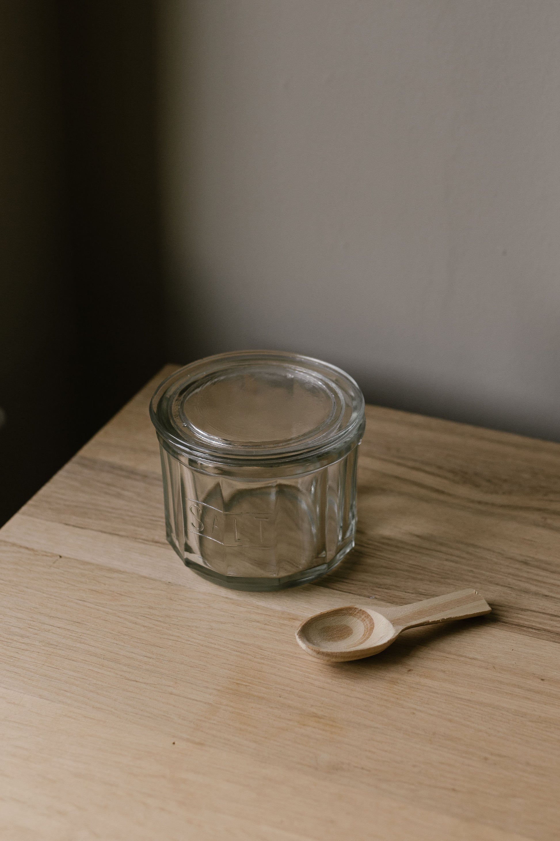 glass salt pot with lid and wooden spoon